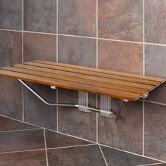 a wooden shelf mounted to the side of a tiled wall next to a shower head