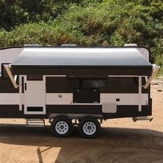 an rv parked on the side of a dirt road with trees in the back ground