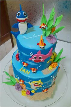 there is a blue cake decorated with an image of shark and fish on it's side