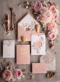 the wedding stationery is laid out on top of the table with pink flowers and greenery