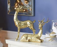 a gold deer statue sitting on top of a white table next to a christmas tree