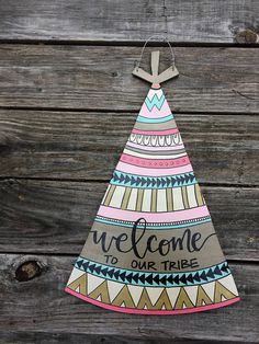 a wooden sign that says welcome to our tribe on it, hanging from a string