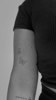 a woman with a small butterfly tattoo on her left arm and the word love is written in cursive writing