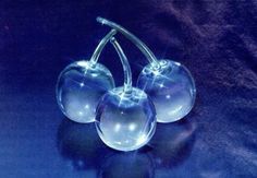 two clear glass cherries sitting on top of a blue surface with light shining through them