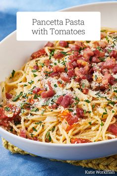 a white bowl filled with pasta covered in ham and cheese on top of a blue table cloth