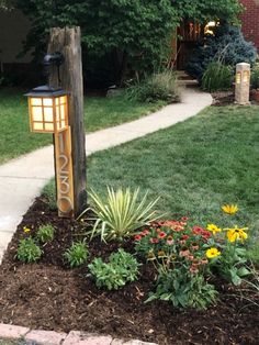 a mailbox sitting on top of a wooden post in the middle of a flower bed