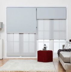 a living room with a couch, chair and table in front of a window that has blind shades on it