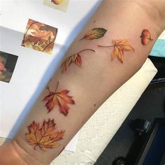 a woman's arm with an orange and yellow fall leaf tattoo on the left forearm