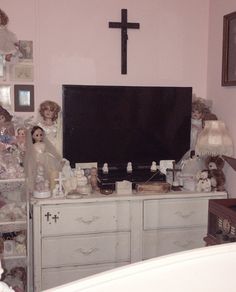 there is a television on top of a dresser in the room with many stuffed animals