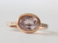 Handmade 14K rose gold east/west set bezel ring featuring a natural oval brilliant cut pink sapphire measuring 8.3 x 6.4 mm and weighing 1.77 cts. The center stone is flanked by pave' set round brilliant cut diamonds weighing 0.12 ct (G,VS2/SI1) 2.1 mm wide band. Size 6, can be resized. The finish can be customized to matte or hammered, please convo us for for more details. *Ready to ship* *SKU 15-101425 Heirloom Rose Gold Oval Sapphire Ring, Oval Pink Sapphire Ring In Rose Gold, Oval Rose Gold Pink Sapphire Ring, Rose Gold Oval Pink Sapphire Ring, Oval Sapphire Ring In Rose Gold With Center Stone, Pink Oval Sapphire Ring With Bezel Setting, Half Eternity Ring Diamond, Full Eternity Ring, Bezel Ring