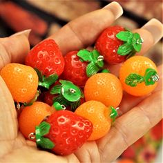 small oranges and strawberries are in the palm of someone's hand