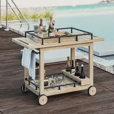 an outdoor bar cart with bottles and glasses on the deck next to a swimming pool