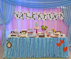 a table topped with lots of cakes and cupcakes next to a sign that says valentine's day