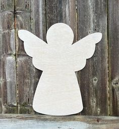 a wooden angel cutout sitting on top of a wooden fence