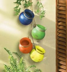 three vases are hanging on the wall next to a potted plant and window sill