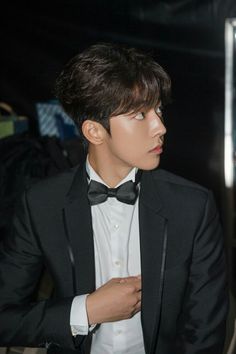 a young man in a tuxedo and bow tie looking off to the side