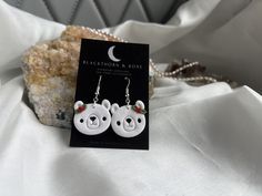 a pair of white bear earrings sitting on top of a bed