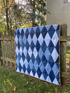 a blue and white quilt hanging on a wooden fence