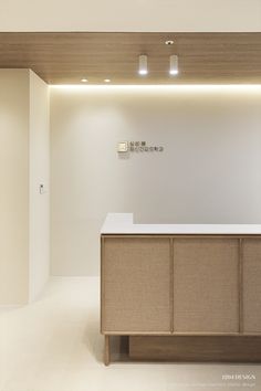 an empty reception area with white walls and wood accents on the wall, along with beige cabinetry