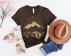 Prepare to embark on a journey of a lifetime with our 'Adventure Awaits' shirt! This shirt is not just a piece of clothing, it's a symbol of endless possibilities and exciting experiences waiting to be discovered. Made with high-quality fabric and featuring a bold and inspiring design, this shirt is perfect for explorers, dreamers, and anyone with a passion for the great outdoors. Whether you're climbing mountains, camping under the stars, or simply seeking new adventures, let this shirt be your Relaxed Fit T-shirt For Summer Adventure, Summer Adventure Short Sleeve Shirt, Summer Travel Tops With Graphic Print, Summer Travel Graphic Tee Tops, Pre-shrunk Summer Adventure Shirt, Pre-shrunk Summer Shirt For Adventure, Pre-shrunk Graphic Tee For Adventure, Pre-shrunk Relaxed Fit Adventure Shirt, Pre-shrunk Relaxed Fit Shirt For Adventure