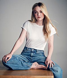 a woman sitting on top of a wooden table with her hands in her pockets and legs crossed