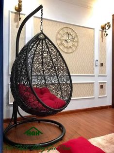 a hanging chair in the middle of a room with a clock on the wall behind it