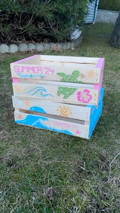 a wooden crate sitting in the grass with flowers painted on it's sides and bottom