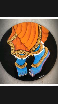 an artistic painting on a black plate with orange and blue colors, depicting a woman's feet