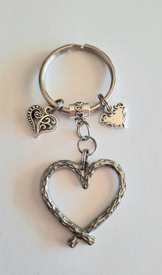 a heart shaped keychain with two charms hanging from it's sides on a white surface