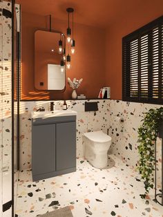 a bathroom with an orange wall and patterned flooring is pictured in this image, it has a sink, toilet, and mirror