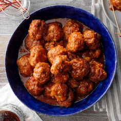 a blue bowl filled with meatballs on top of a table next to other food