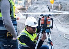 a man in safety vest and hard hat holding a tripod