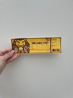 someone is holding up a ticket for the lion king show on broadway in front of a white wall