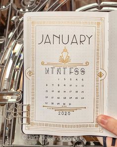 a hand holding up a calendar in front of a metal rack