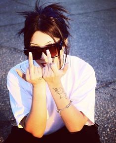 a woman sitting on the ground holding her hands up to her face with one hand