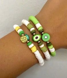 three bracelets with green and white beads are on the arm of a woman's hand