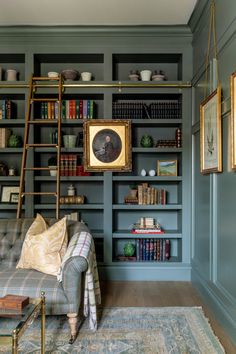 a living room with bookshelves, couch and pictures on the wall behind it