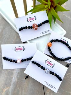 three bracelets with black beads are sitting on a table next to a potted plant