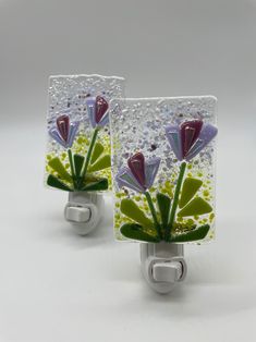 two glass magnets with flowers on them sitting next to each other in front of a white background