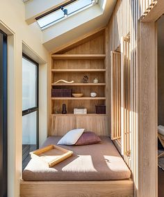 a bed sitting under a skylight in a bedroom next to a wooden shelf filled with books