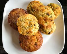 four muffins on a white plate sitting on a table