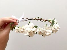 a hand holding a flower crown with white flowers