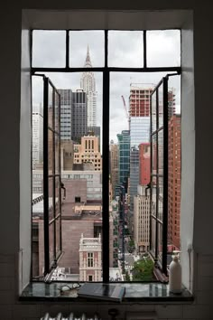 an open window looking out onto a cityscape with tall buildings in the distance