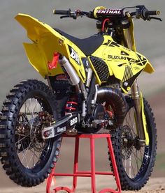 a yellow dirt bike sitting on top of a red stand