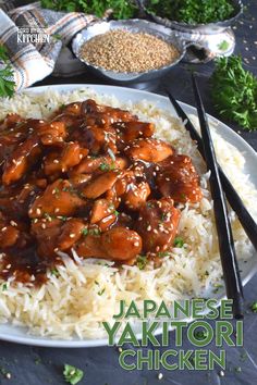 a plate with rice and meat on it next to some chopsticks in the background