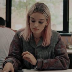 a woman with pink hair sitting at a table