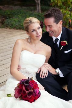 a bride and groom sitting on a wooden deck