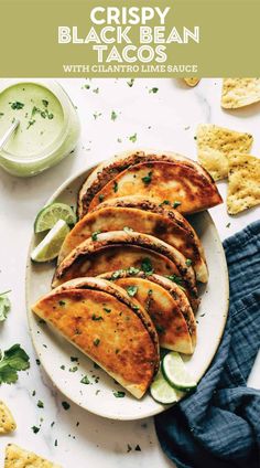 a white plate topped with quesadillas next to chips and lime wedges