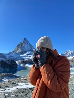 a person standing on top of a mountain talking on a cell phone with mountains in the background