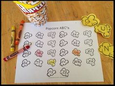 popcorn abc's with crayons next to it on a table and some candy